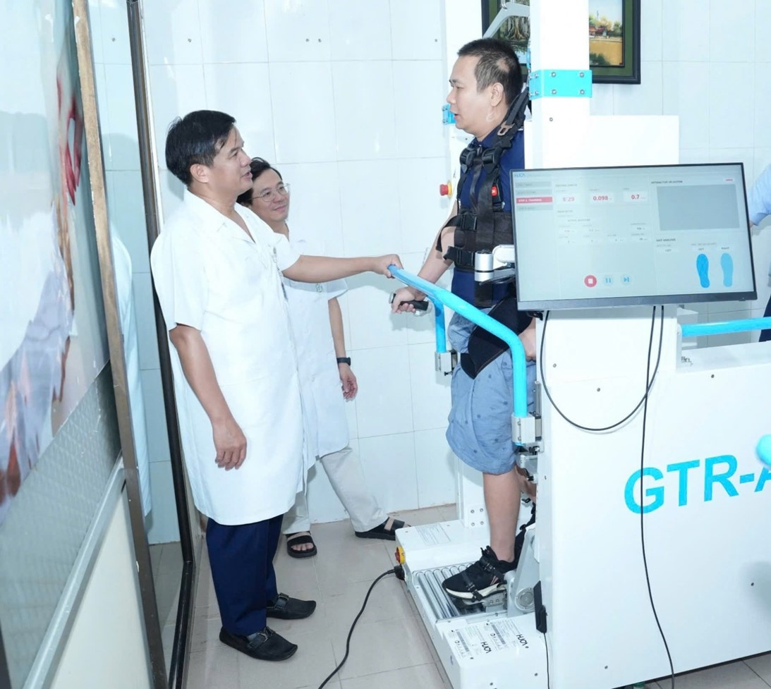 PGS.TS Đào Xuân Cơ - Giám đốc Bệnh viện thăm hỏi bệnh nhân tập phục hồi chức năng bằng Robot. Ảnh: BVCC