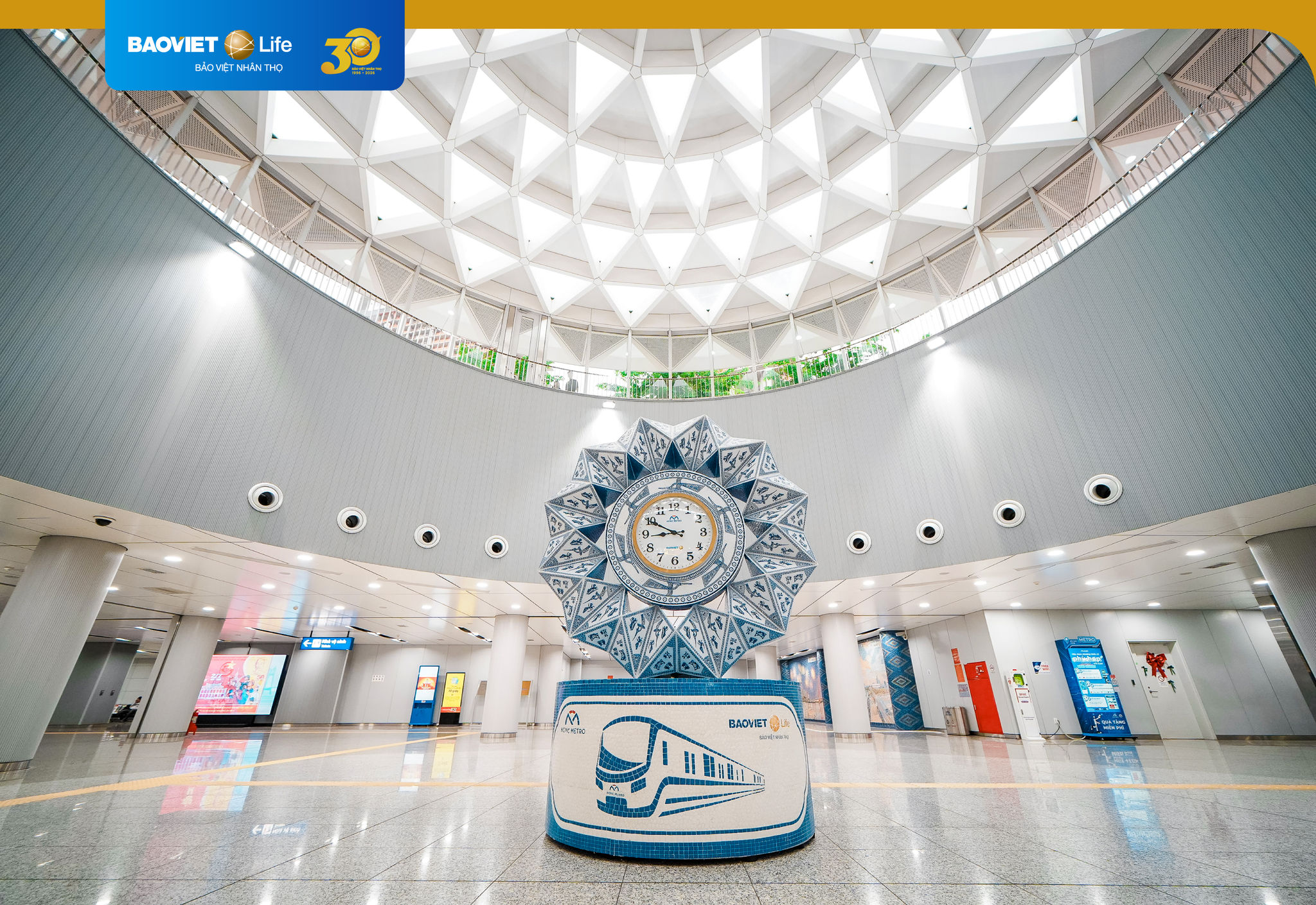 Anh 1_Không gian trung tâm ga Metro Bến Thành với điểm nhấn là Tháp đồng hồ gốm và giếng trời hoa sen cách điệu.