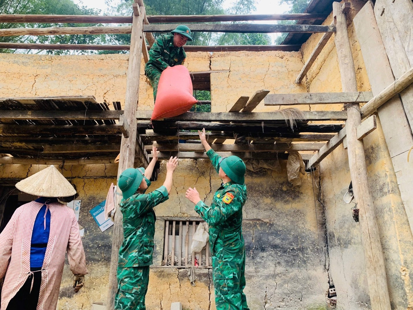 Cán bộ, chiến sĩ Bộ đội Biên phòng tỉnh Tuyên Quang hỗ trợ người dân di chuyển đồ đạc ra khỏi căn nhà vách đất đã xuống cấp để chuẩn bị xây dựng nhà ở mới.