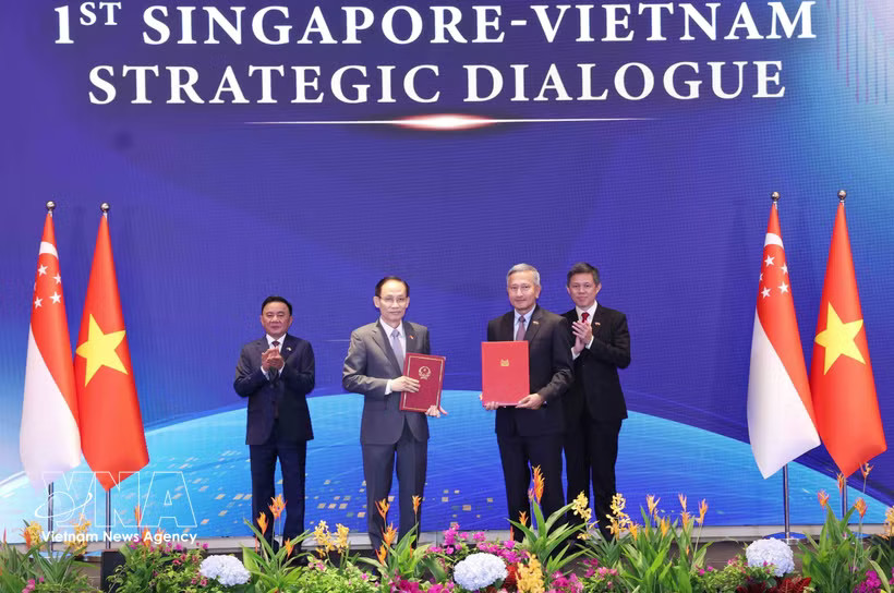 Vietnam's Politburo member and Minister of Foreign Affairs Le Hoai Trung (first row, left) and Singaporean Minister for Foreign Affairs Vivian Balakrishnan exchange the Vietnam-Singapore Joint Statement on Technology Connectivity Strategy. (Photo: VNA) 