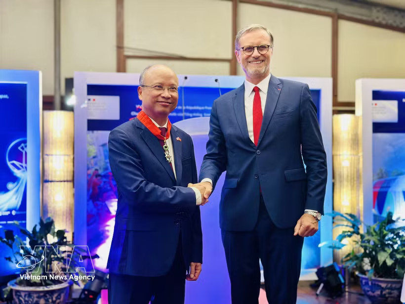 Authorised by the French President, French Ambassador to Vietnam Olivier Brochet gives the noble order to Former Vietnamese Ambassador to France Dinh Toan Thang at a ceremony in Hanoi on August 26 (Photo: VNA)