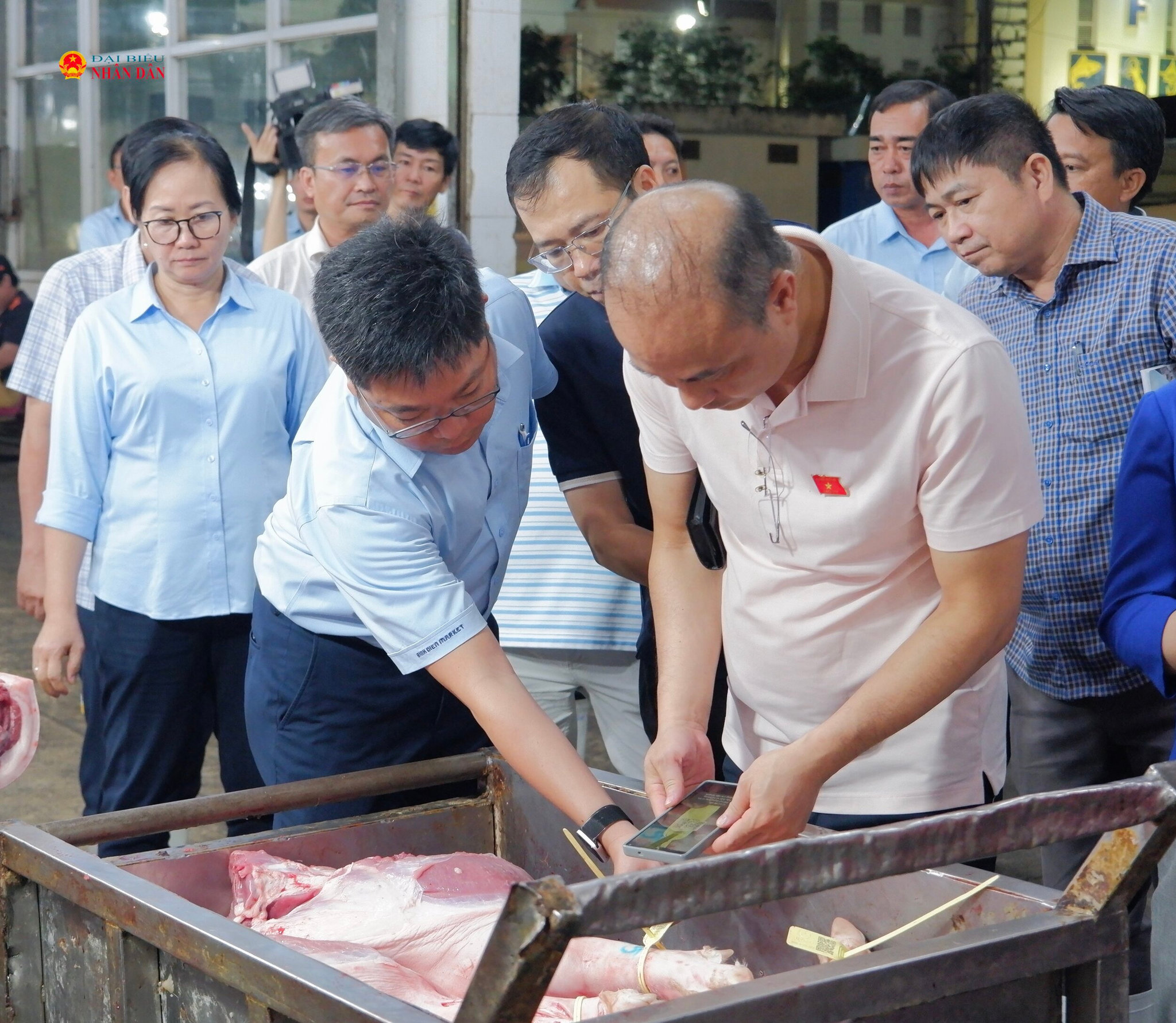 Phó Chủ nhiệm Ủy ban Khoa học, Công nghệ và Môi trường Nguyễn Phương Tuấn check mã QR kiểm tra truy xuất nguồn gốc thịt heo tại chợ đầu mối Bình Điền