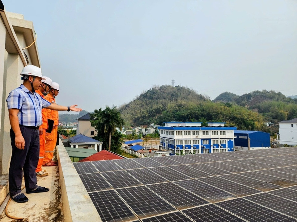 Nhân viên Điện lực và khách hàng kiểm tra hệ thống điện mặt trời mái nhà. Ảnh NPC