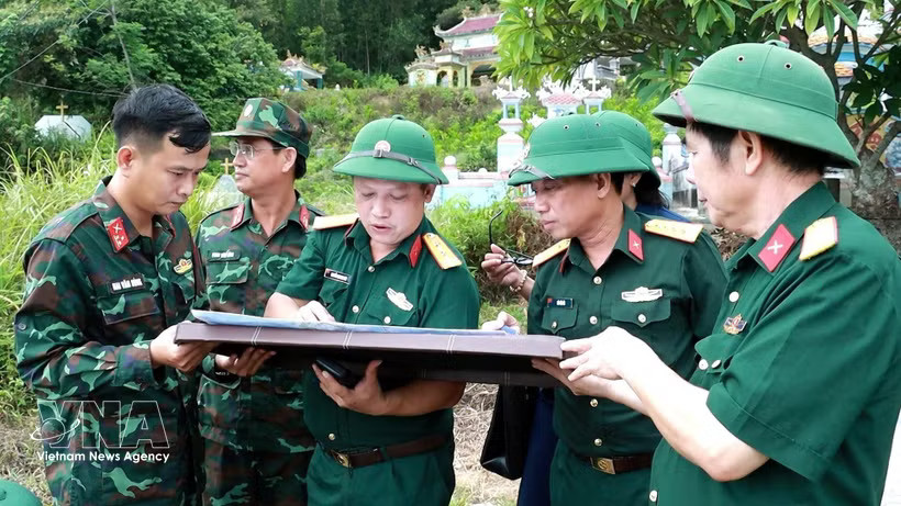 Colonel Ha Van Ai, Deputy Political Commissar of the Hue City Military Command (third, left), and other officials discuss the burial location of fallen soldiers on a map. (Photo: VNA)