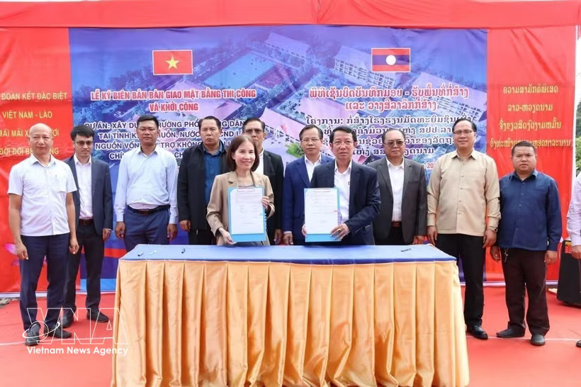 Participants sign a handover and acceptance record for the construction site and break ground for a project to build the Khammuon provincial Boarding School for Ethnic Minority Students. (Photo: VNA)