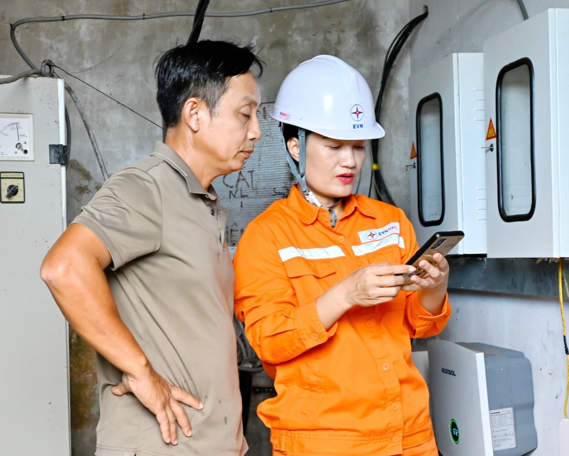 Nhân viên Điện lực Cẩm Xuyên, Công ty Điện lực Hà Tĩnh hướng dẫn khách hàng theo dõi hệ thống điện mặt trời mái nhà qua app trên điện thoại thông minh. Ảnh NPC