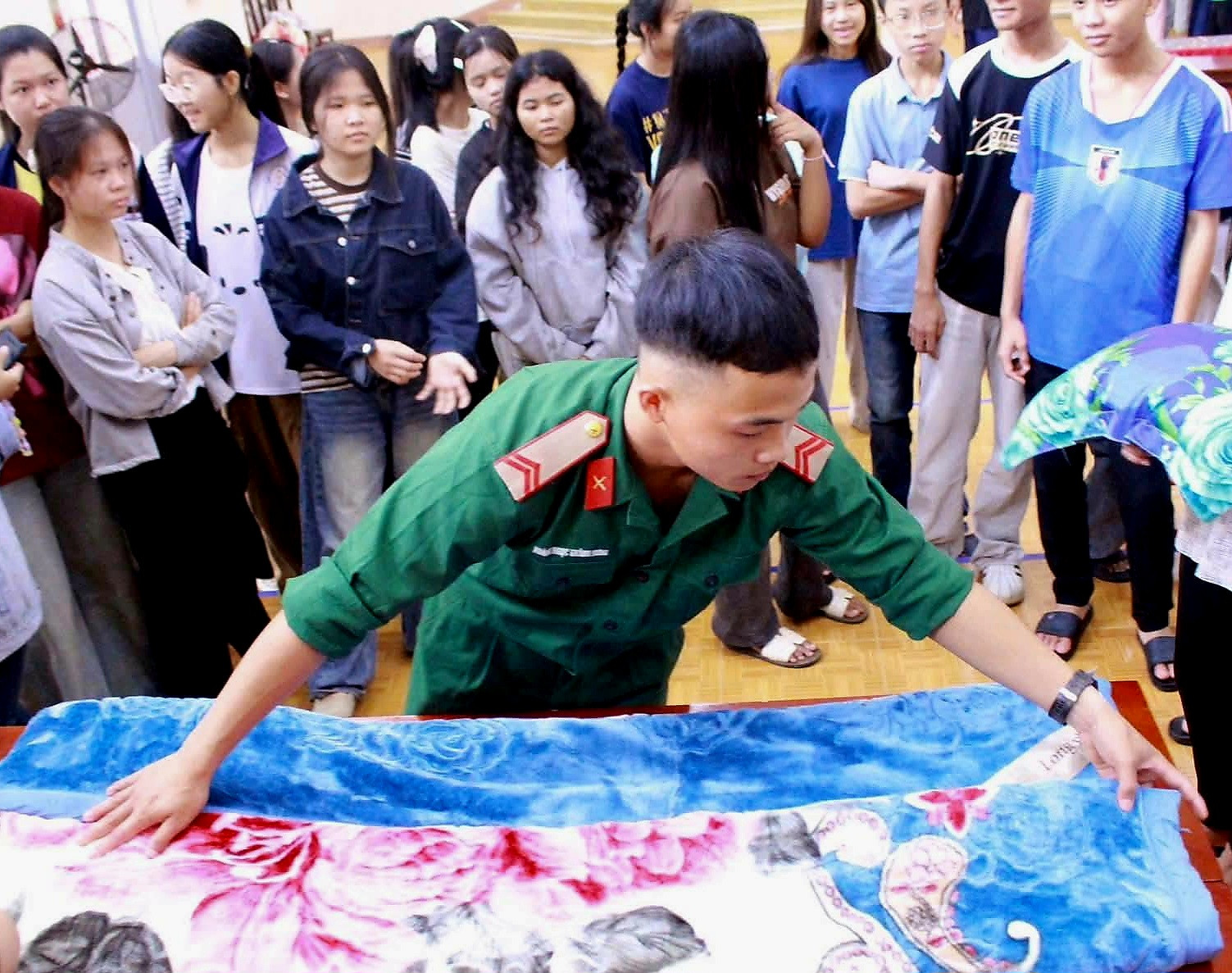 Chiến sĩ Trung đoàn 584 hướng dẫn học sinh Trường PTDTNT THPT N’Trang Lơng thực hành gấp chăn, rèn luyện nền nếp, tác phong trong sinh hoạt hàng ngày