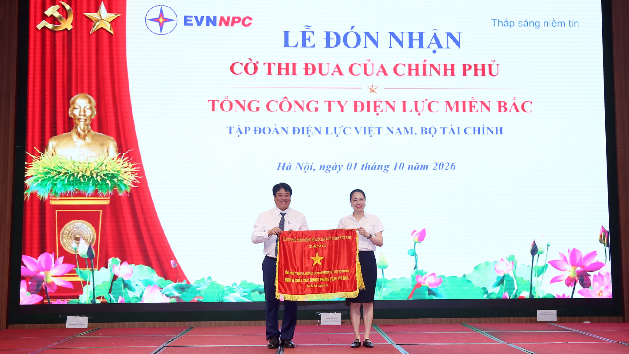Thừa ủy quyền của Thủ tướng Chính phủ, ông Nguyễn Anh Tuấn – Phó Bí thư Đảng ủy, Thành viên HĐTV, Tổng Giám đốc EVN trao Cờ Thi đua của Chính phủ cho bà Đỗ Nguyệt Ánh – Bí thư Đảng ủy, Chủ tịch HĐTV EVNNPC, đại diện