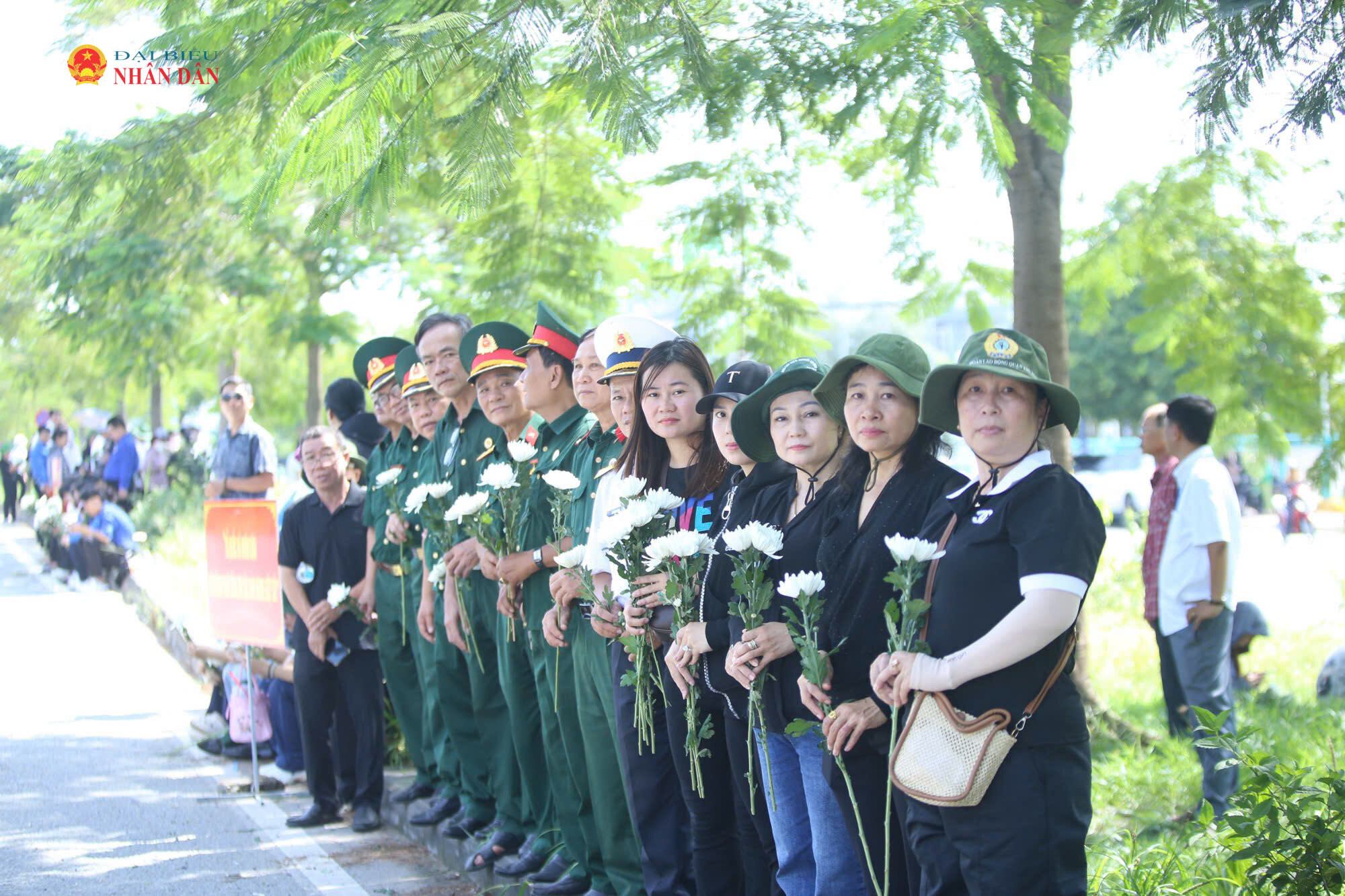 Tại khu vực Khu du lịch Suối Tiên, đông đảo cựu chiến binh, người dân phường Tăng Nhơn Phú mang theo hoa cúc trắng, đứng thành hàng dọc bên đường Võ Nguyên Giáp chờ đưa tiễn các Anh hùng liệt sĩ
