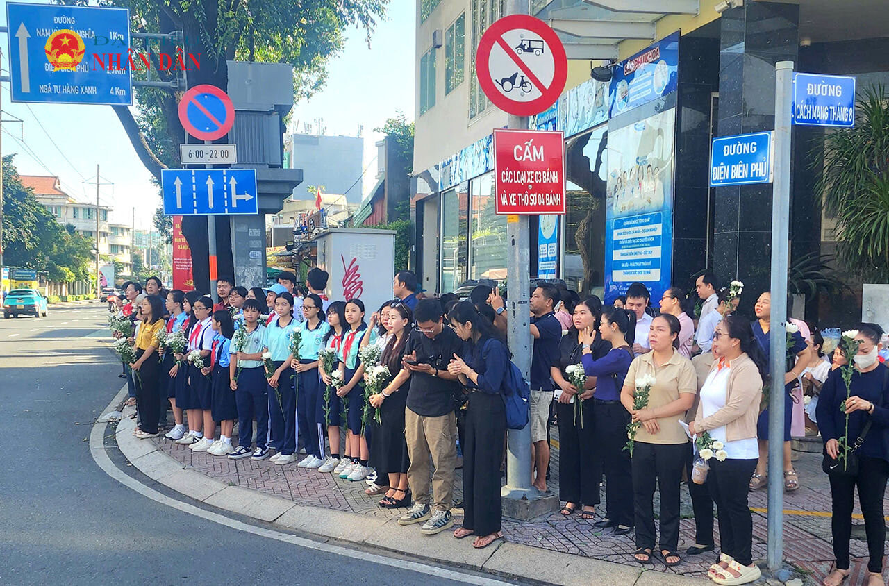 Tại giao lộ Cách Mạng Tháng Tám - Điện Biên Phủ rất đông cựu chiến binh, người dân, học sinh cầm hoa cúc trắng, cờ tổ quốc đứng hai bên đường chờ tiễn đưa các anh hùng liệt sĩ. Ảnh Nguyễn Tuấn
