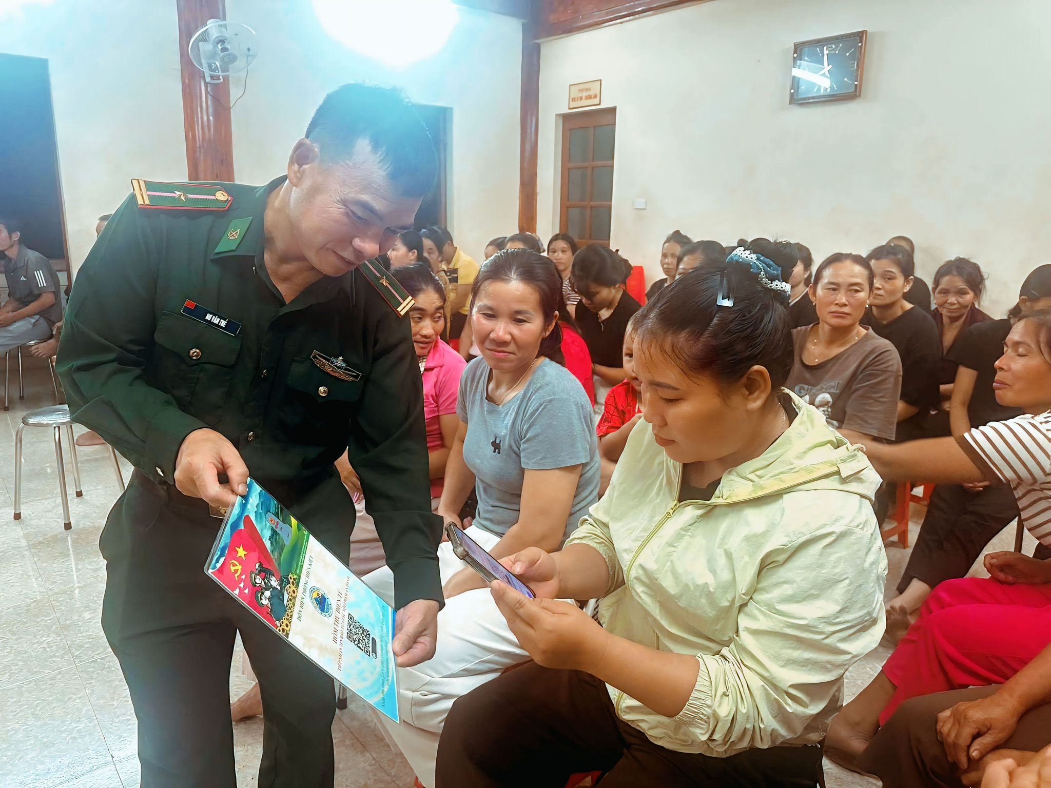 Cán bộ Đồn Biên phòng Hiền Kiệt hướng dẫn người dân sử dụng điện thoại thông minh, tiếp cận thông tin và các tiện ích số tại buổi tuyên truyền