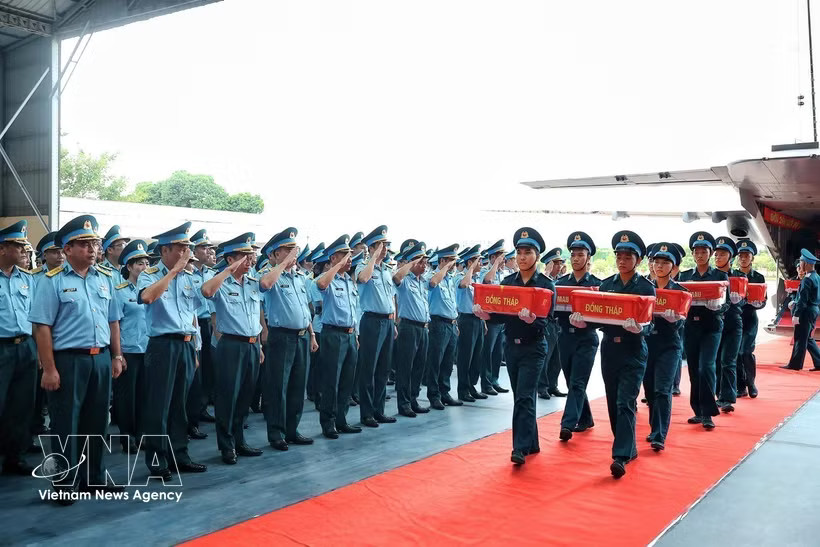 Officers and soldiers of the Air Defense - Air Force Service perform a salute as the remains of martyrs from localities within Military Region 9 are unloaded from the aircraft at Gia Lam military airfield in Hanoi on October 5, 2026. (Photo: VNA)